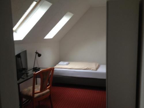 a bedroom with a bed and a chair and a window at Hotel Saarland Lebach in Lebach