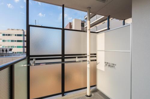 a room with sliding glass doors in a building at Ostay Shin-Osaka Hotel Apartment in Osaka