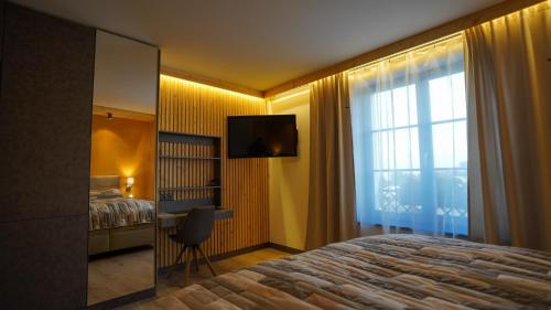 a bedroom with a bed and a television and a window at Sousedi Pavlov in Pavlov
