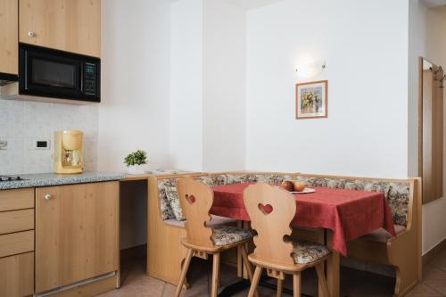 a kitchen with a table with a red table cloth on it at Apparthotel Sellaronda in Arabba
