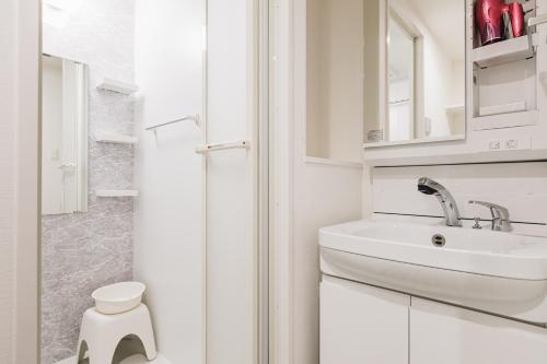 a white bathroom with a sink and a shower at Ostay Shin-Osaka Hotel Apartment in Osaka