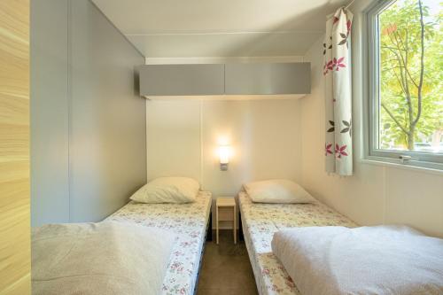 two beds in a small room with a window at DS One Vacances, Prairies de la Mer in Grimaud