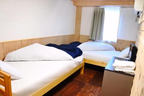 two beds in a room with a window at SappoLodge in Sapporo