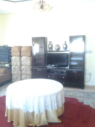 a living room with a table and a tv at Maison d'hôtes afoulki tafraout in Tafraoute