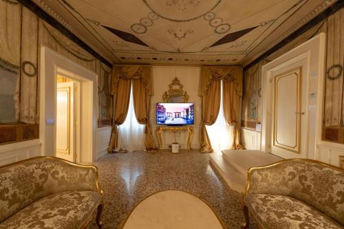 a living room with two chairs and a television at Ca' Bonfadini Historic Experience in Venice