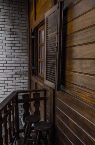 a balcony with two stools and a door and a window at Pousada Aracê in Pedra Azul