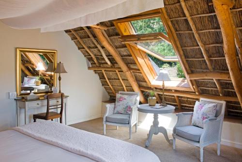 1 dormitorio con 1 cama, mesa y sillas en Rickety Bridge Manor House en Franschhoek