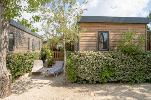 a house with two chairs and a tree at DS One Vacances, Prairies de la Mer in Grimaud