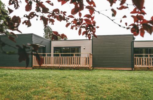 une maison avec une terrasse en bois dans une cour dans l'établissement Terres de France - Le Domaine du Moulin Neuf, à Rochefort-en-Terre