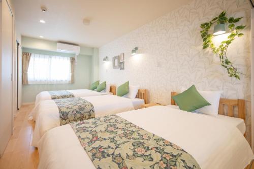 a hotel room with three beds in it at Hotel Haabesu Okinawa in Urazoe