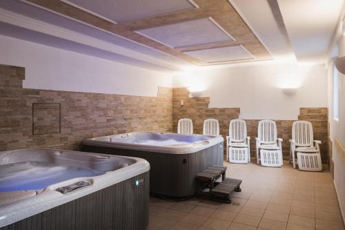 baño grande con bañera de hidromasaje y sillas en Apparthotel Sellaronda, en Arabba