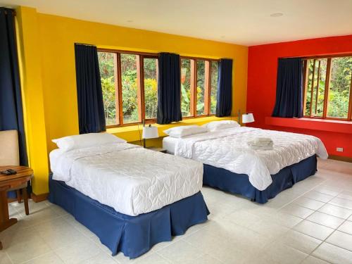 2 camas en una habitación con paredes rojas y amarillas en La Casa de Cariari Al Golf, en Heredia