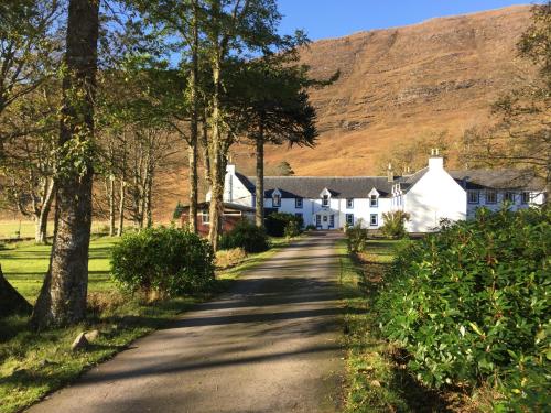 ein Haus auf einer Straße mit einem Berg im Hintergrund in der Unterkunft Hartfield House Hostel in Applecross