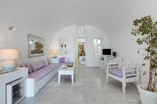 a living room with a purple couch and a fireplace at Iliovasilema Hotel & Suites in Imerovigli