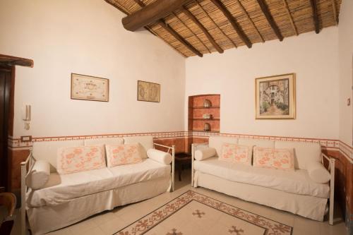 a living room with two white couches and a rug at Hotel Anticos Palathos in Orosei
