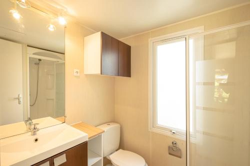 a bathroom with a toilet and a sink and a window at DS One Vacances, Prairies de la Mer in Grimaud