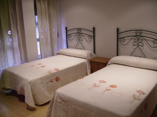 2 letti in una stanza con lenzuola bianche e fiori di Hotel Delphos a Moraleja