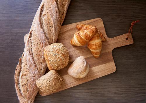 First Hotel Stockholm North في أوبلاندز فاسبو: لوح تقطيع خشبي عليه كرواسون وخبز