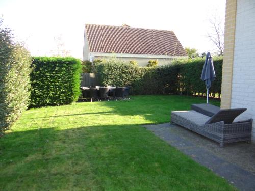 a backyard with a table and a couch and an umbrella at Vakantievilla Noordzee in Kamperland