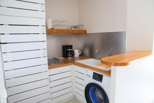 a small kitchen with white cabinets and a dishwasher at MANGANAO LOFTS INN Bord de Mer in Saint-François