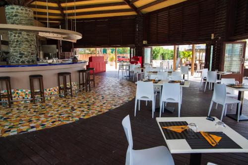 a restaurant with white tables and chairs and a counter at MANGANAO LOFTS INN Bord de Mer in Saint-François