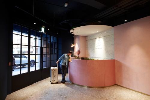 a man standing at a counter with a suitcase in a room at Mr.Mantter in Taichung