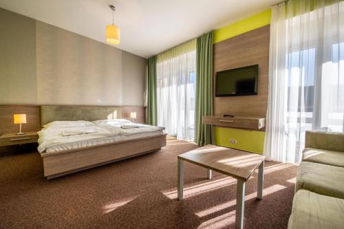 a bedroom with a bed and a tv and a couch at Hotel Lučivná in Lučivná