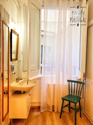 a bathroom with a sink and a mirror and a chair at Hostal Portugal in Barcelona
