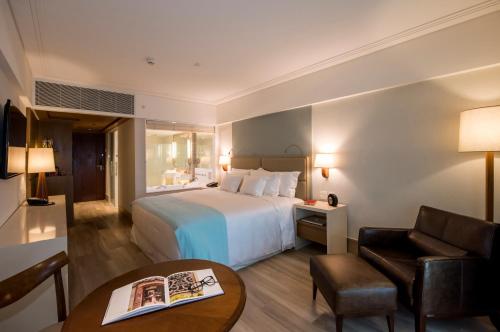 a hotel room with a bed and a chair and a table at Vogal Luxury Beach Hotel & SPA in Natal