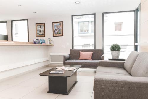 a living room with two couches and a coffee table at Terres de France - Appart'Hotel Quimper Bretagne in Quimper