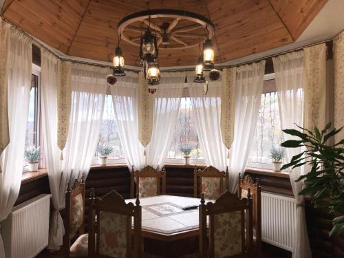 a dining room with white curtains and a table and chairs at Polyanskiy Zamok in Polyana