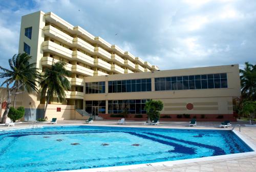 a building with a large swimming pool in front of a building at Ramada by Wyndham Princess Belize City in Belize City
