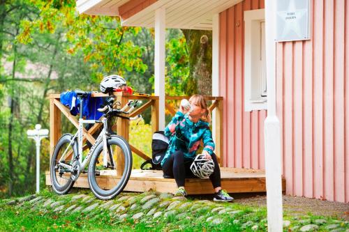 Una bambina seduta su un portico vicino a una bicicletta di Lisebergsbyns Stugor a Göteborg