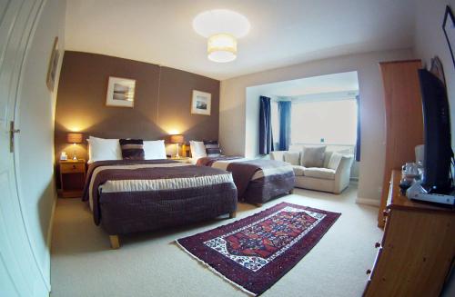 a hotel room with two beds and a couch at Glyn Peris Guest House in Llanberis