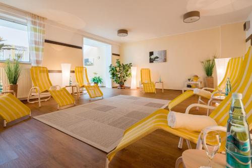 a living room with yellow chairs and a rug at Waldhotel Schäferberg in Espenau