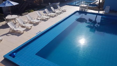 an overhead view of a swimming pool with chairs and an umbrella at Pousada do Albatroz in Cabo Frio