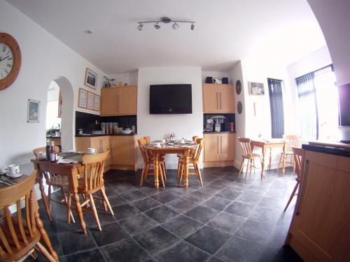 a kitchen and dining room with tables and chairs at Glyn Peris Guest House in Llanberis