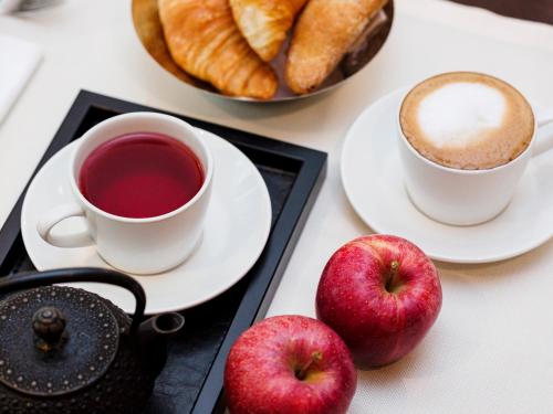 two apples and two cups of coffee on a table at Boutique Hotel Helmhaus Zürich in Zurich