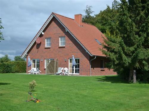 a red brick house with two chairs in a yard at Ferienhof Heimberg - Bowe GbR in Sauensiek