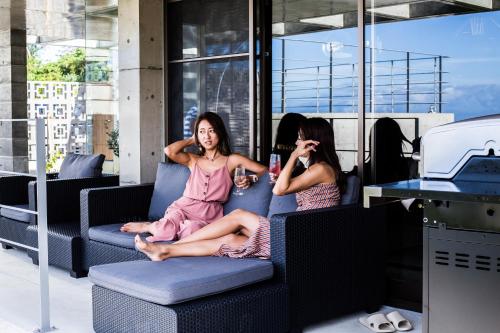 two women sitting on a couch talking on their cell phones at -Musée Villa- in Nakijin