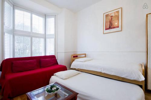 a room with two beds and a red couch at Arsenal 123 in London