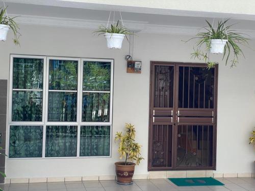 a house with windows and a door with potted plants at HILLVIEW HOMESTAY in Tanah Rata