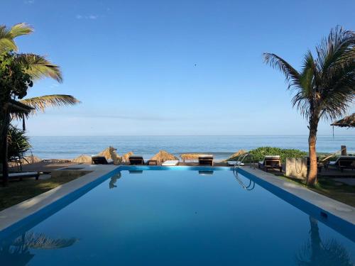 a swimming pool with the ocean in the background at Los Cocos de Vichayito in Vichayito