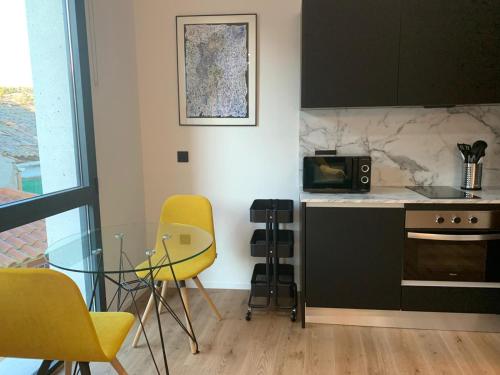 a kitchen with a glass table and yellow chairs at Párpados, casa con jacuzzi para dos in Mélida