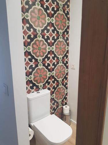 baño con aseo y papel pintado con motivos florales en Dos Alas Rojas, casa con jacuzzi para dos personas en Mélida