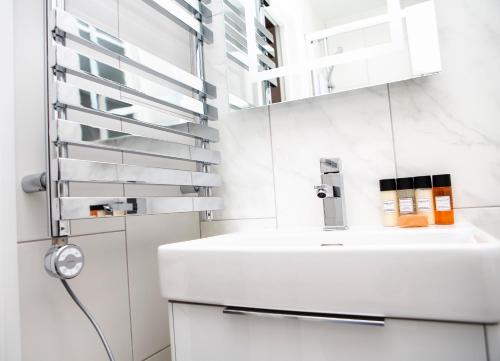 a white bathroom with a sink and a mirror at Carnaby Studios by Indigo Flats in London