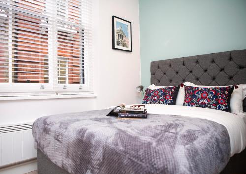 a bedroom with a large bed with a bedspread and a window at Carnaby Studios by Indigo Flats in London