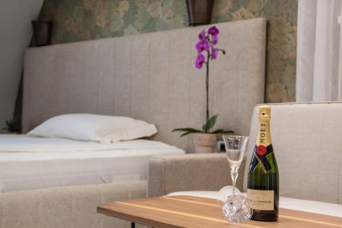 a bottle of champagne sitting on a table next to a bed at Garni Boutique Hotel Arta in Novi Sad