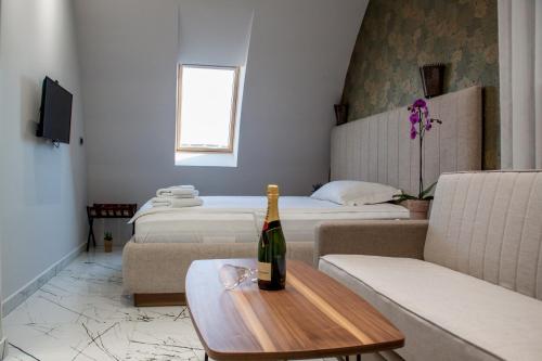 a room with two beds and a bottle of wine on a table at Garni Boutique Hotel Arta in Novi Sad