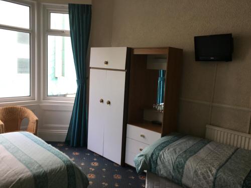 ein Hotelzimmer mit einem Bett, einer Kommode, einem Bett und einem Fenster in der Unterkunft Walford Hotel in Blackpool